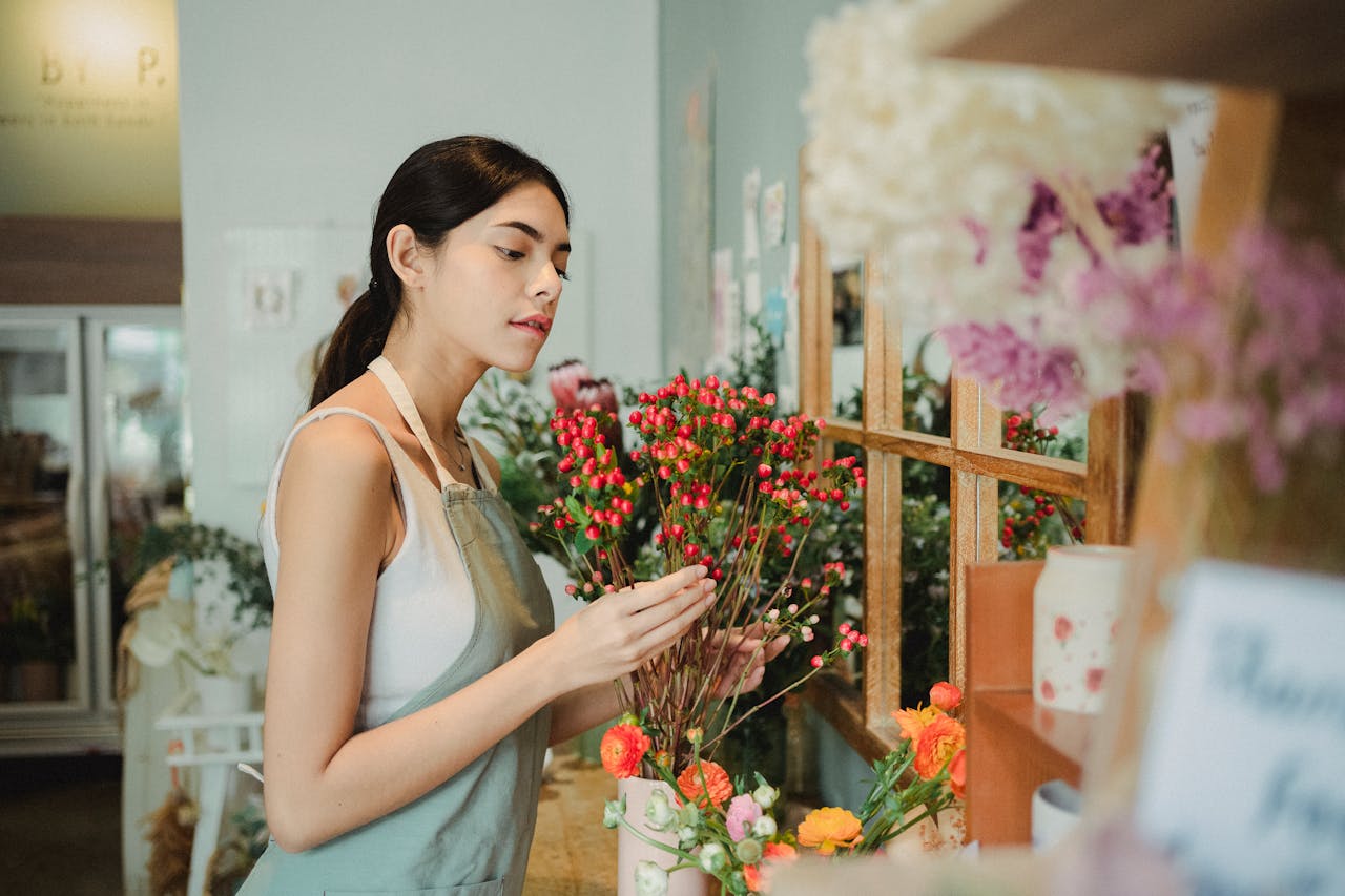 cta-image A female florist arranging colorful flowers in a shop, wearing an apron.